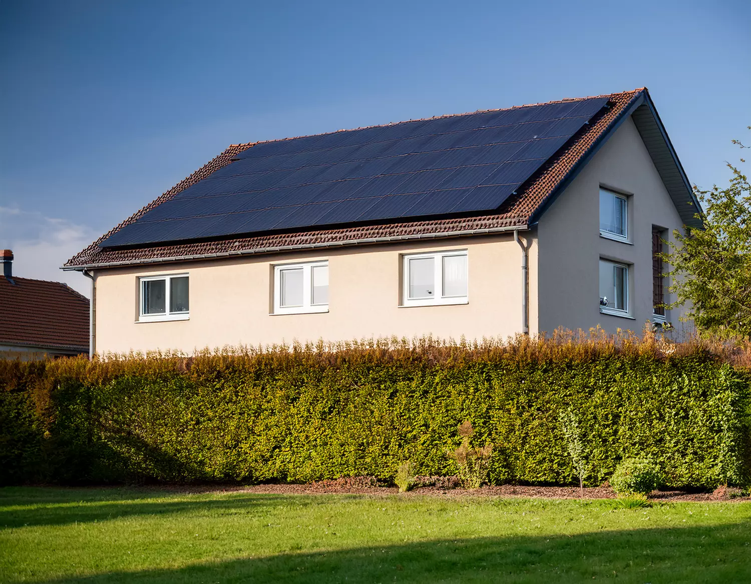 Einfamilienhaus mit Photovoltaikanlage auf dem Satteldach, vom Garten aus